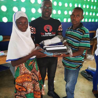 West Africa Mission Coordinator Br. Abu distributing school materials to one of the beneficiaries from Ahmadiyya Muslim Secondary School and her uncle
